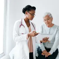 Female doctor showing digital tablet to senior patient 